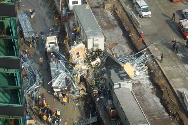 Photograph of firefighters trying to remove debris from the crushed trailer